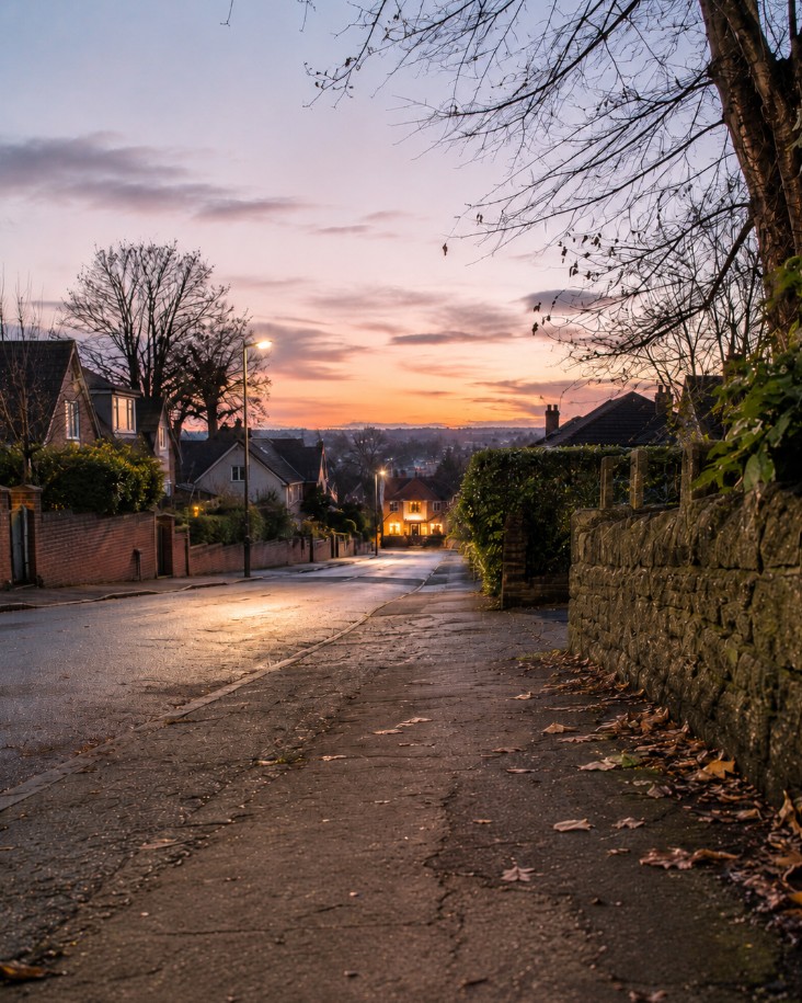 A child looking toward a lit home at dusk, wondering how to reach home without a phone